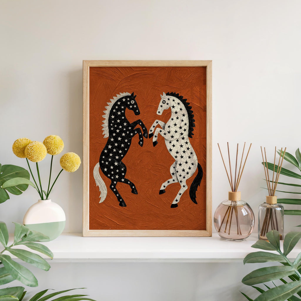 Framed western horse wall art on a clean white shelf with yellow blooms, striking rust orange backdrop and rearing horse silhouettes with stars