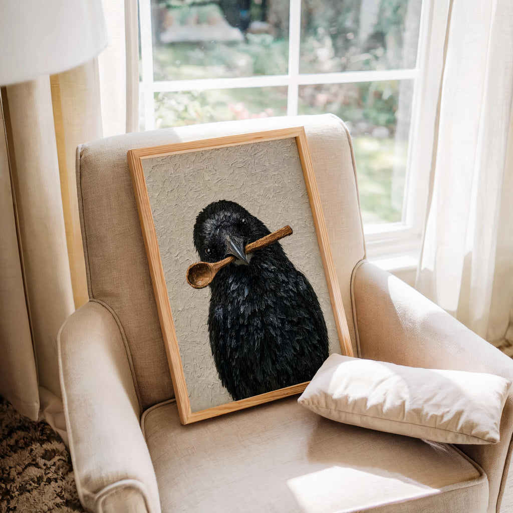 Funny crow wall art propped on an upholstered armchair by a window, textured print, creepy cute bird gift idea