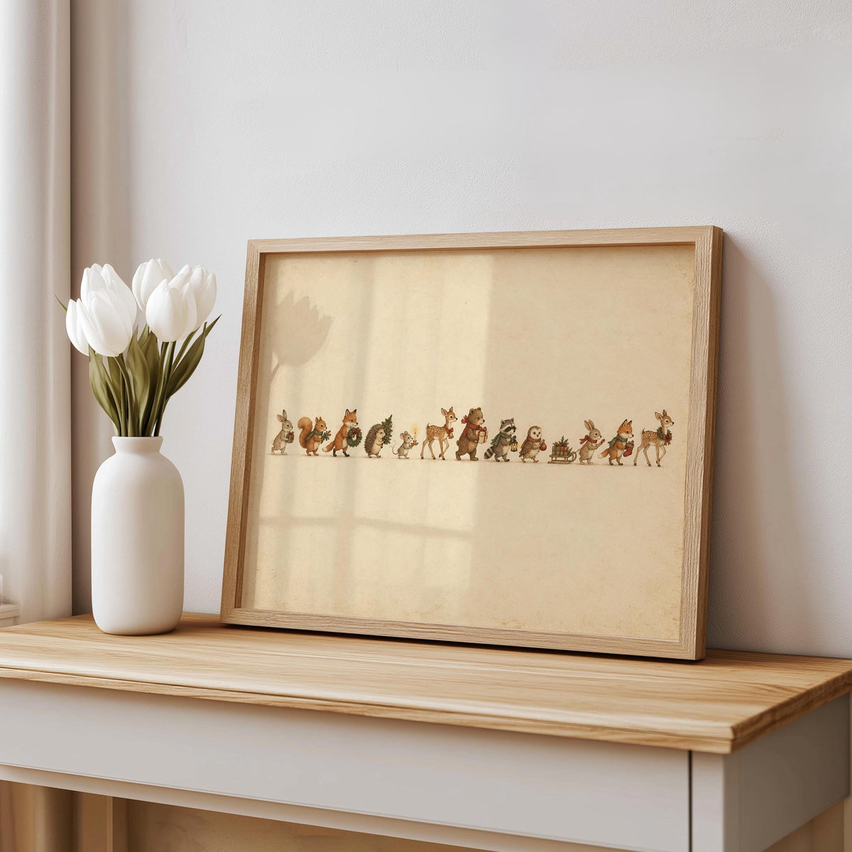 Woodland animal Christmas print in a distressed frame on a console, white vase with tulips nearby
