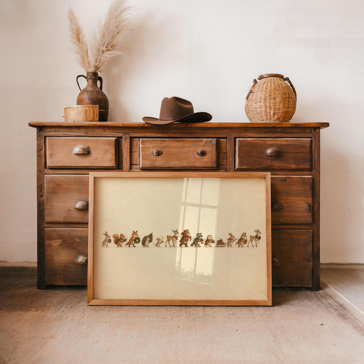 Woodland animal Christmas print propped on an antique wooden dresser, pampas grass and warm tones
