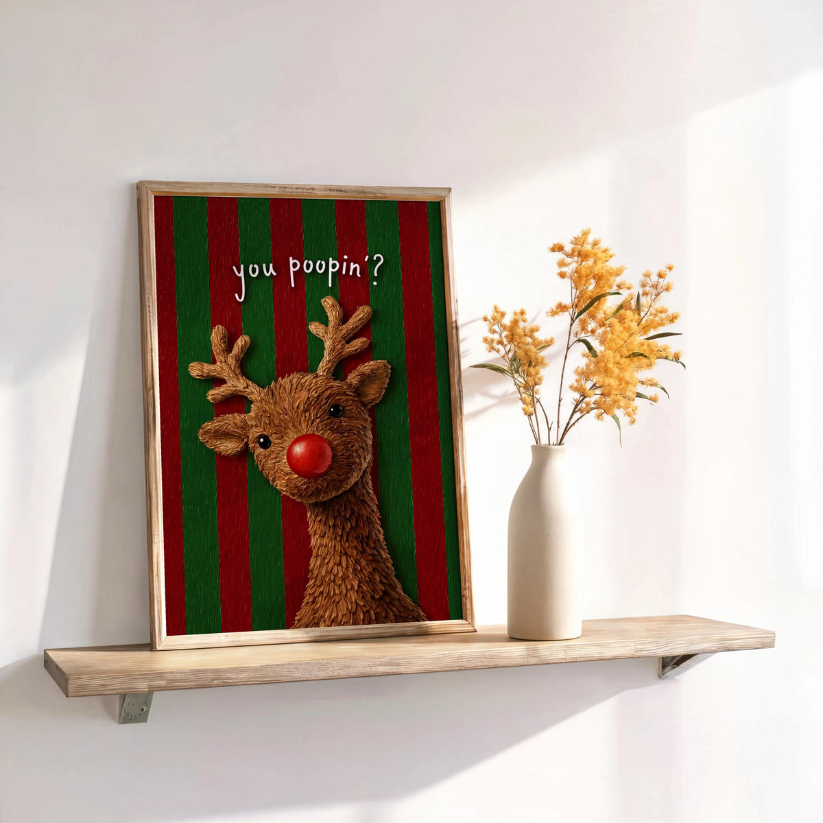 Framed red and green striped Rudolph on shelf, holiday guest bathroom decor setup, funny Rudolph bathroom decor display