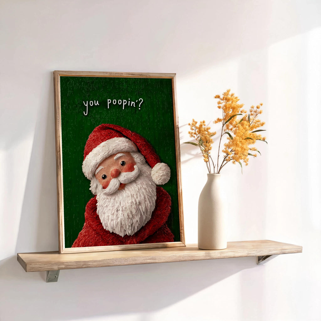 Green-background framed print sits on a floating shelf beside dried stems, smiling Santa with textured vintage look, Christmas loo sign and funny Christmas bathroom sign.