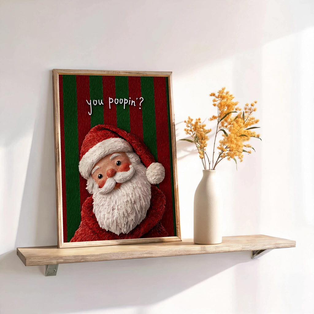 Small framed print leaning on a shelf, red and green vertical stripes behind Santa, Santa Claus bathroom print and funny Christmas bathroom sign.