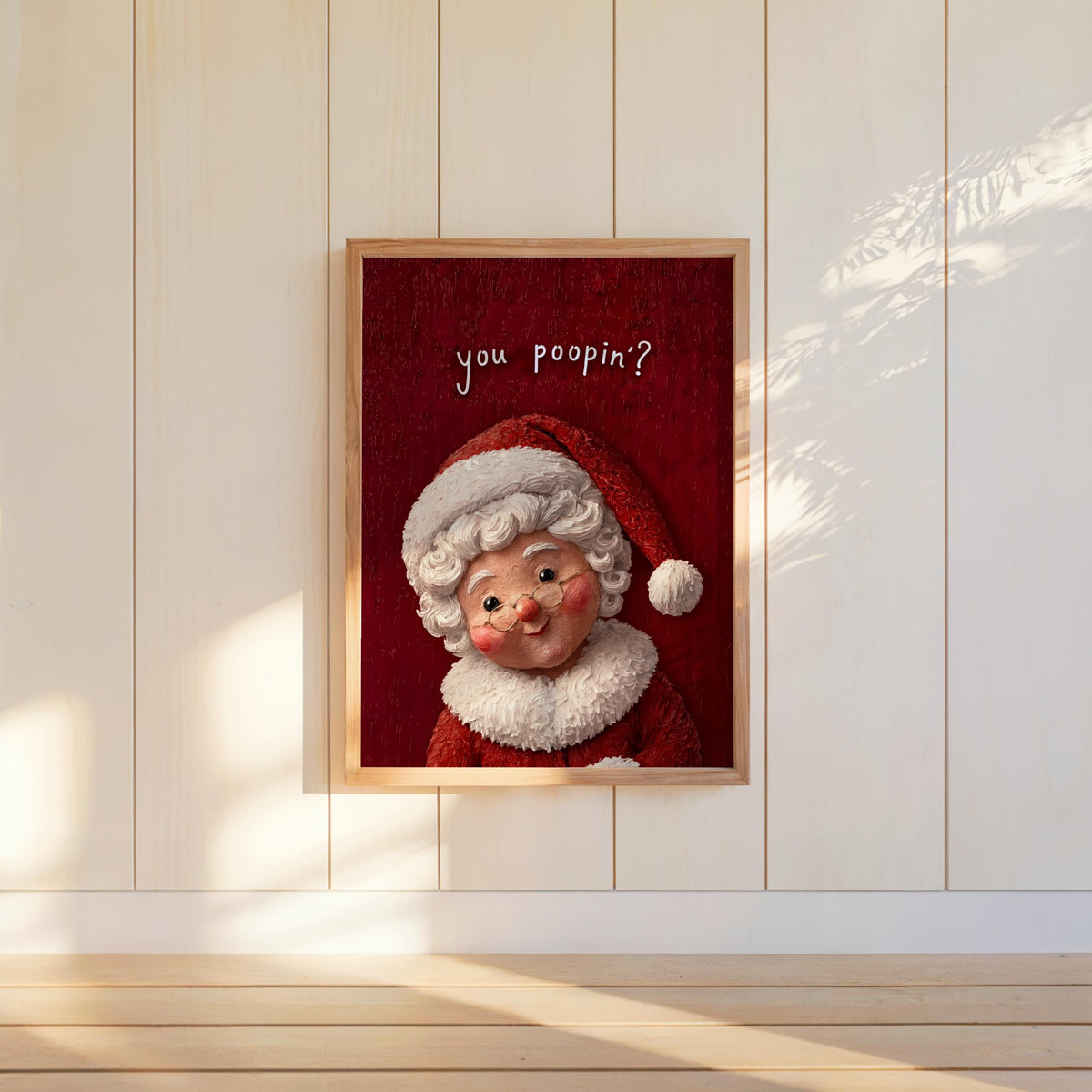 Vertical red-background Mrs Claus poster hung on white paneling, cheeky 'You poopin?' message, funny Christmas bathroom wall art