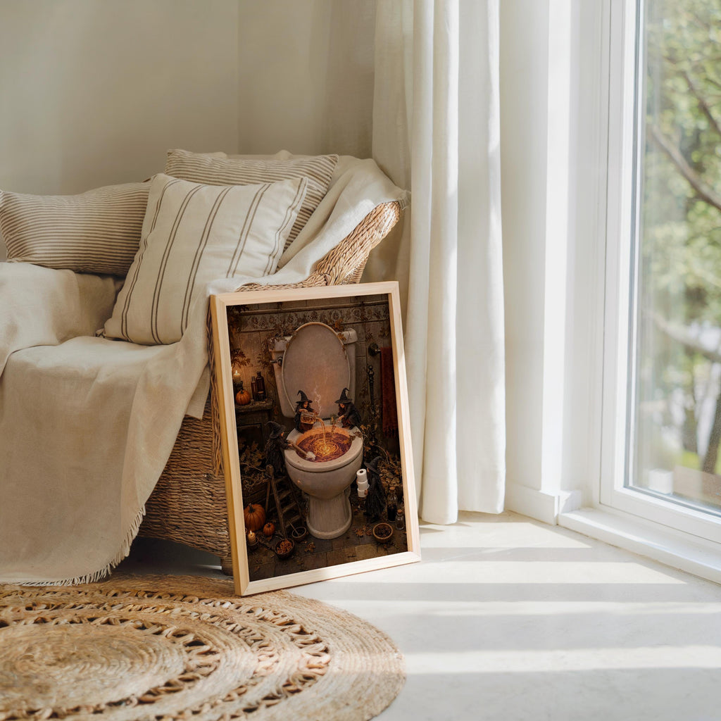 Small framed spooky toilet wall art leaning near a cozy armchair and woven rug, funny bathroom wall decor.
