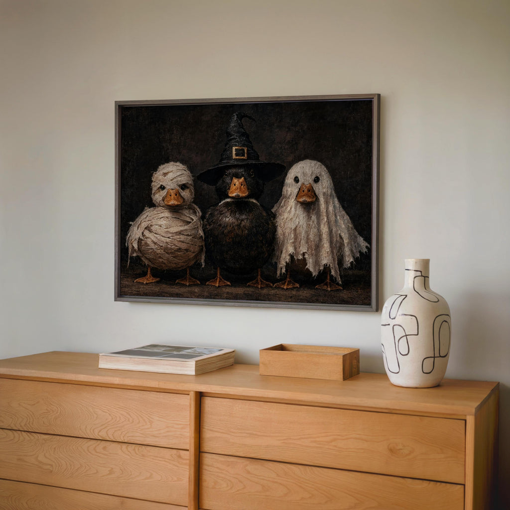 Hung Halloween duck wall art above a low dresser with ceramic vase and pumpkin, spooky duck decor, autumn styling in gray tones