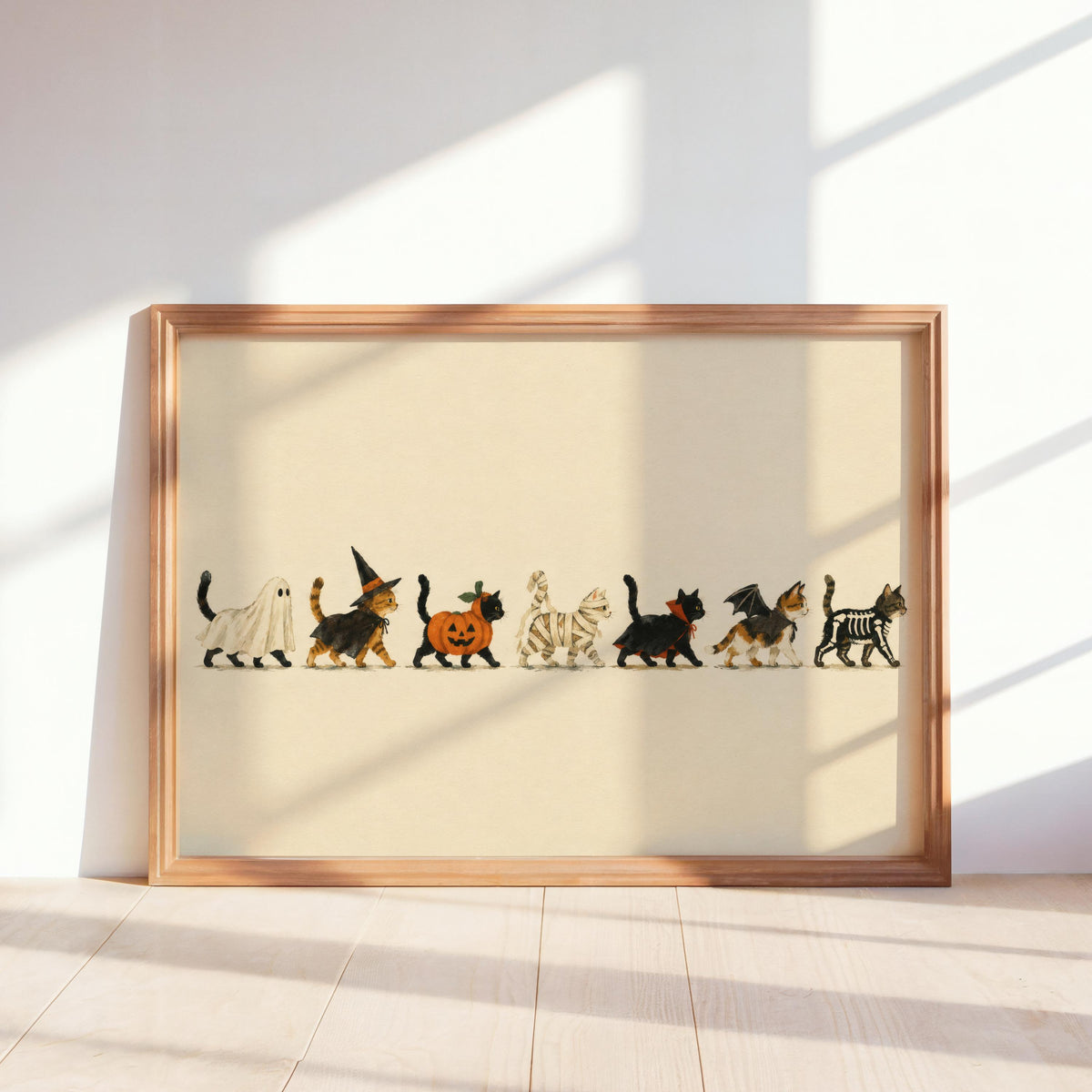 Framed horizontal Halloween cat wall art leaning on sunlit floor, cream background, playful parade.
