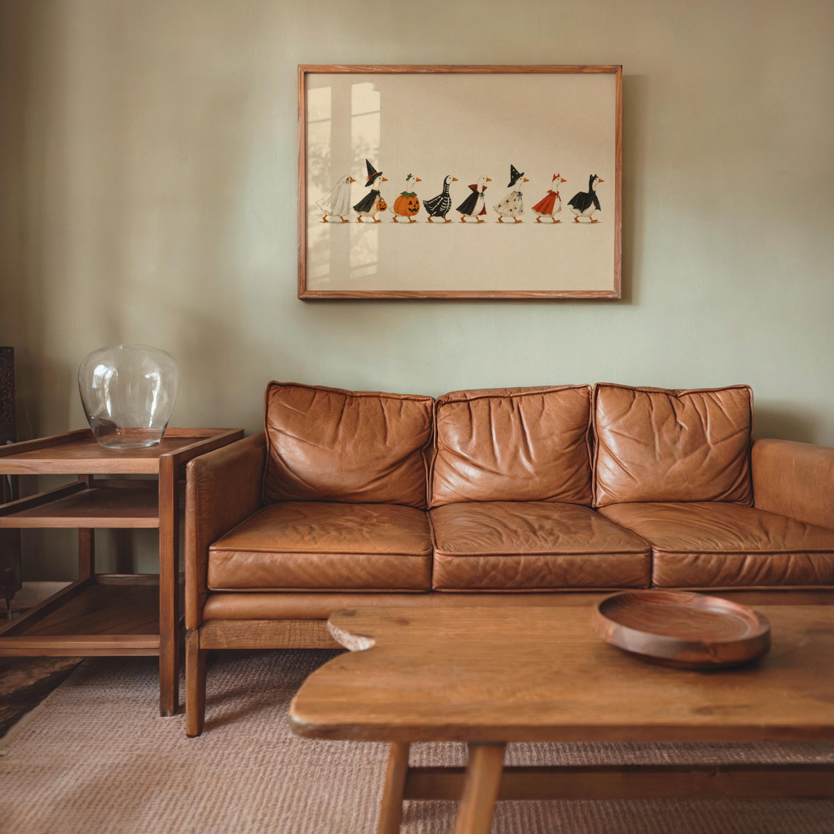 Halloween duck print framed above leather sofa, warm living room styling, rustic Halloween wall decor vibe