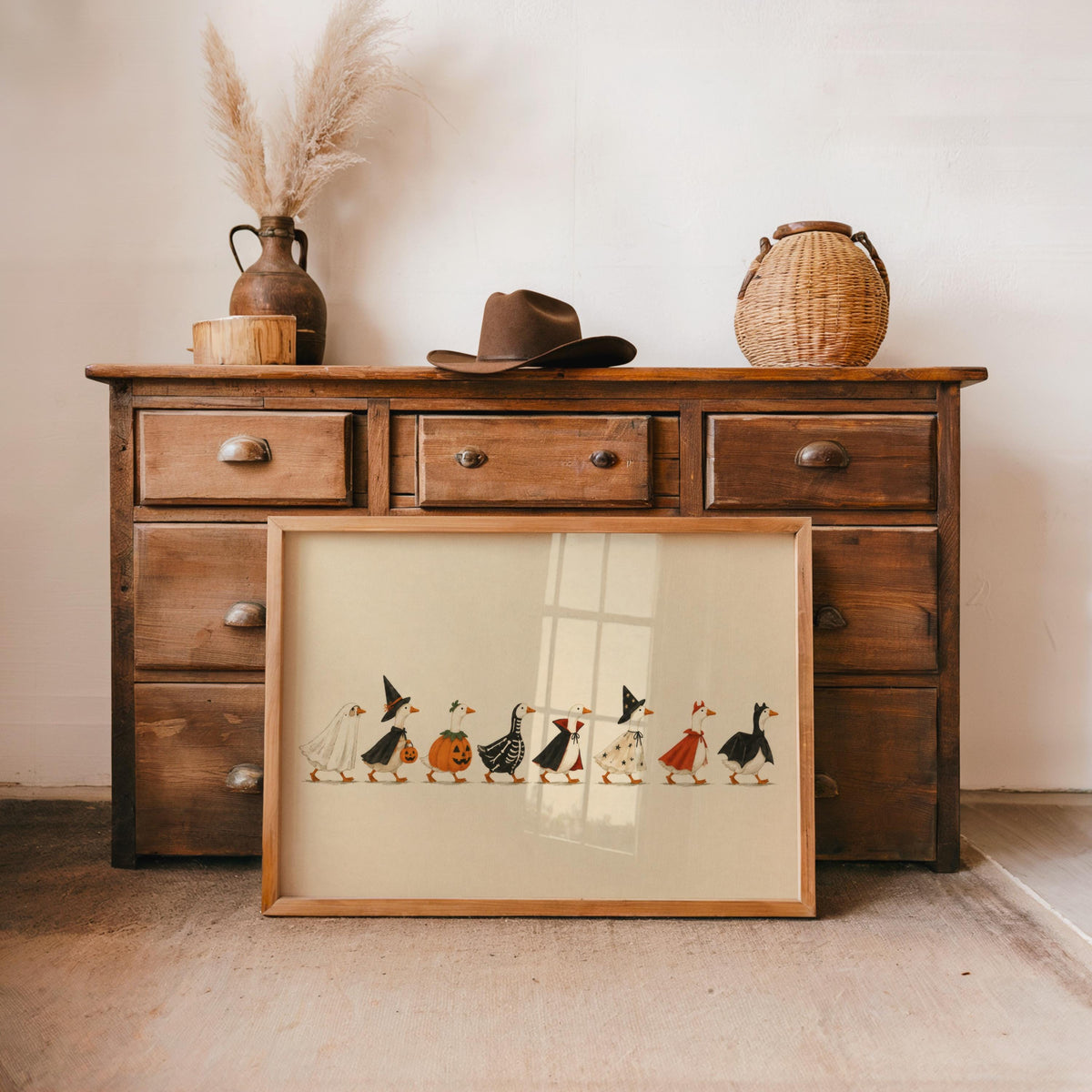 Rustic dresser vignette, vintage Halloween print propped below, cream paper, simple linework ducks