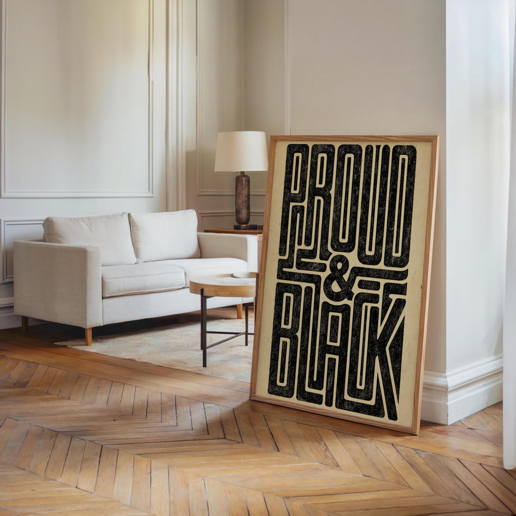 Tall Proud and Black poster placed near a modern sofa, hardwood floor, 70s black wall art statement in room