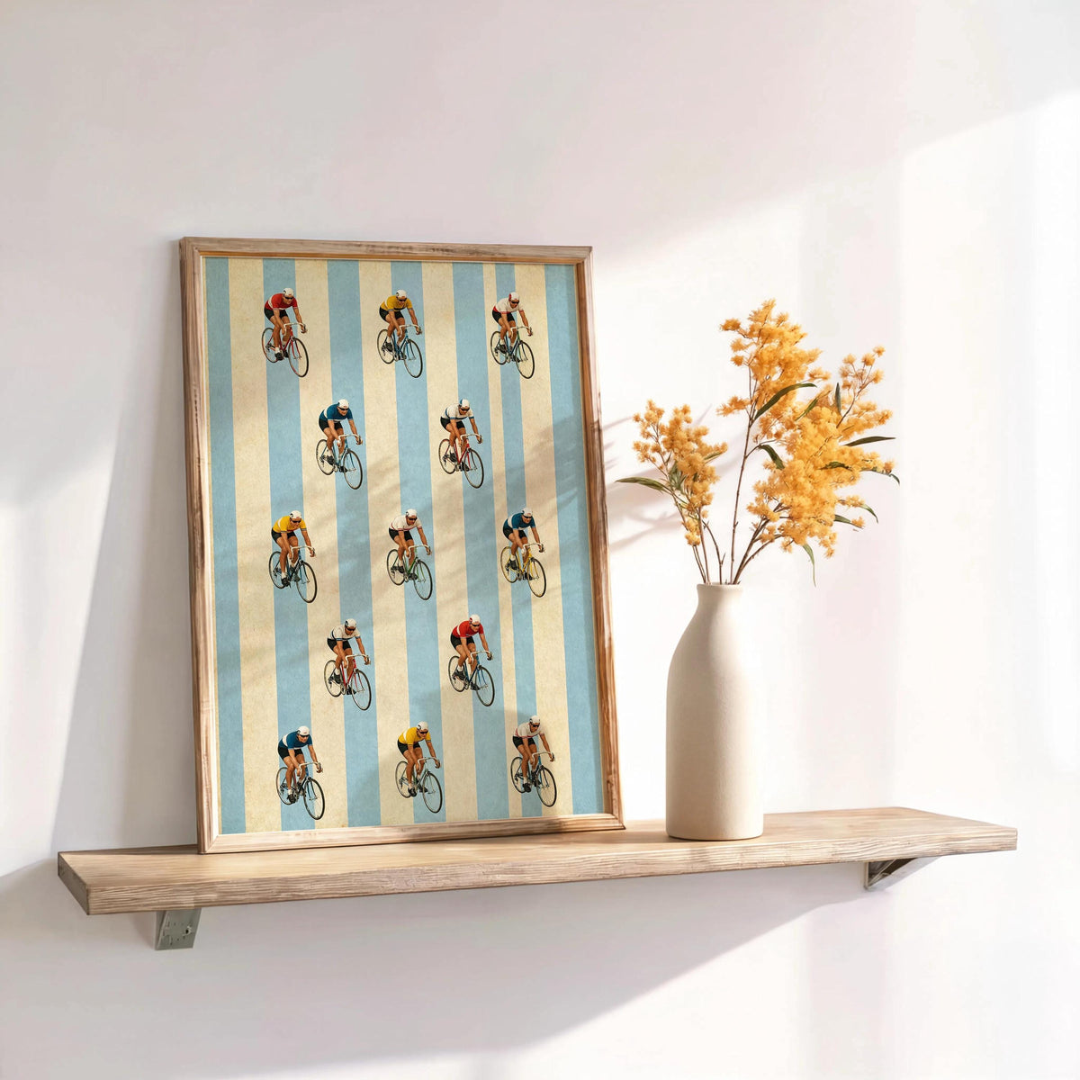 Small framed retro cycling wall art propped on ledge, red and navy jerseys pop against blue stripes.