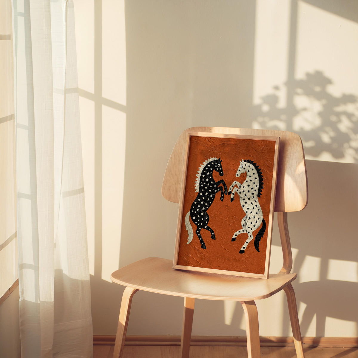 Small framed rearing horse wall decor perched on a wooden chair by a sheer curtain, warm glow, cowgirl room decor with bold black and white horses