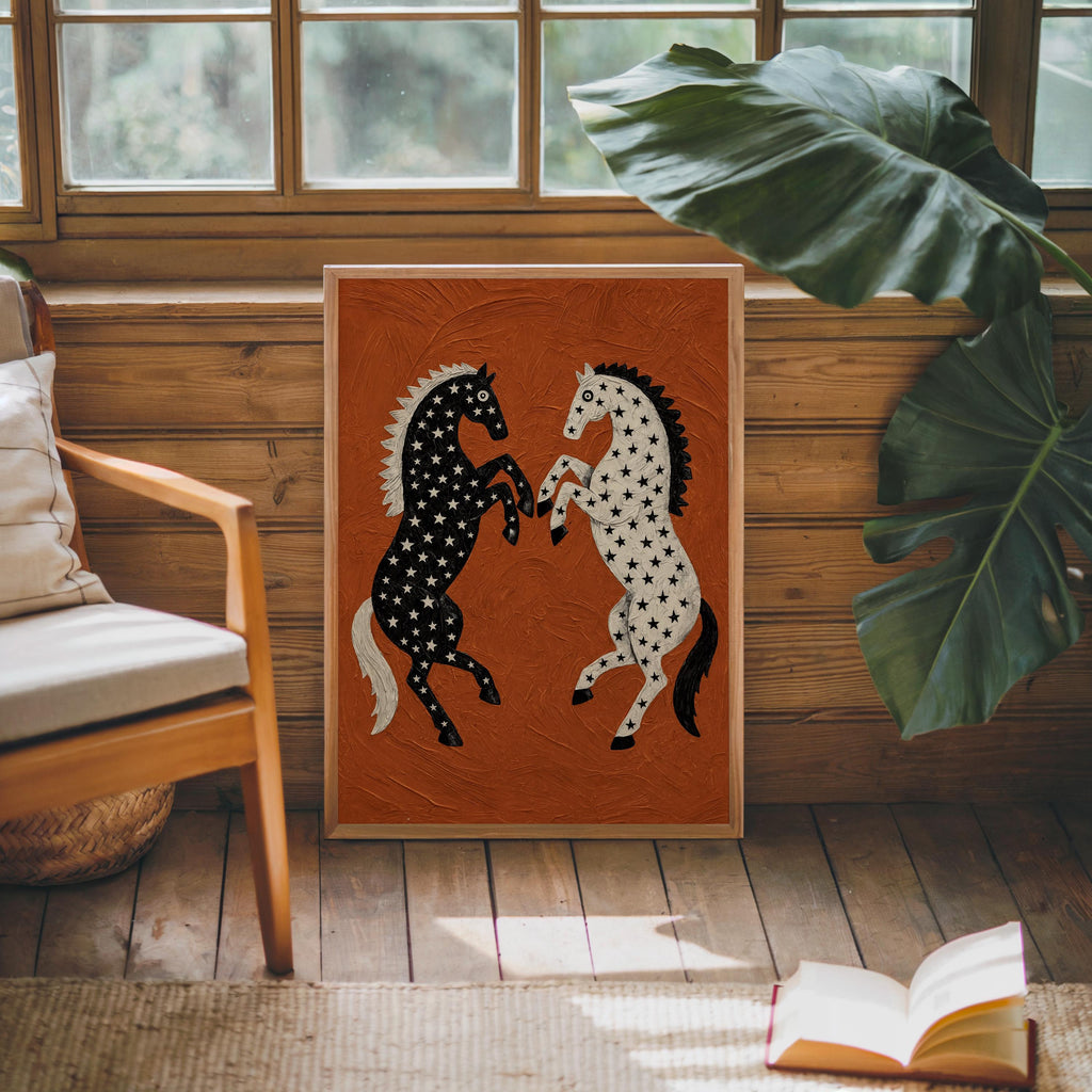 Square black and white horse print propped by a chair and large leafy plant, sunlit rustic window seat, star pattern horse art on rust orange