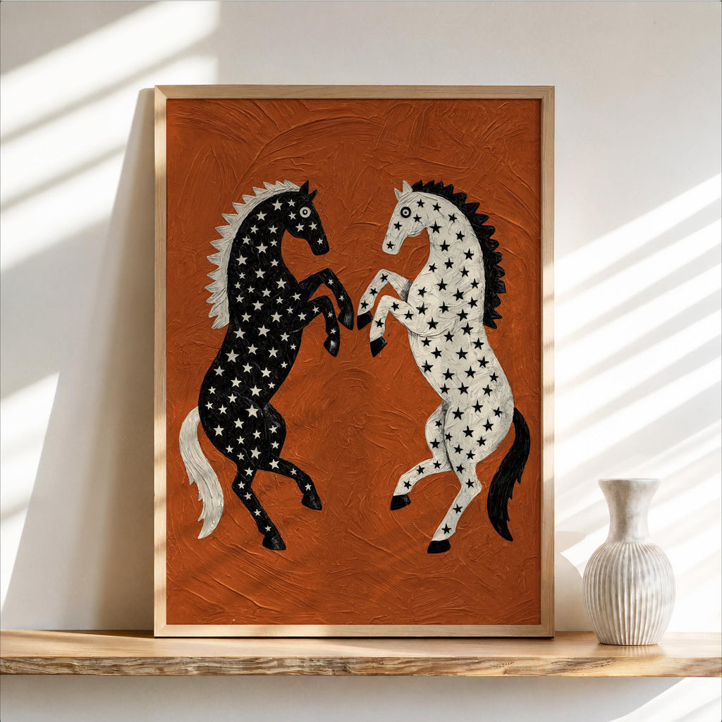 Framed western horse wall art on a shelf, rust orange background, black and white rearing horses with star patterns, small ceramic vase