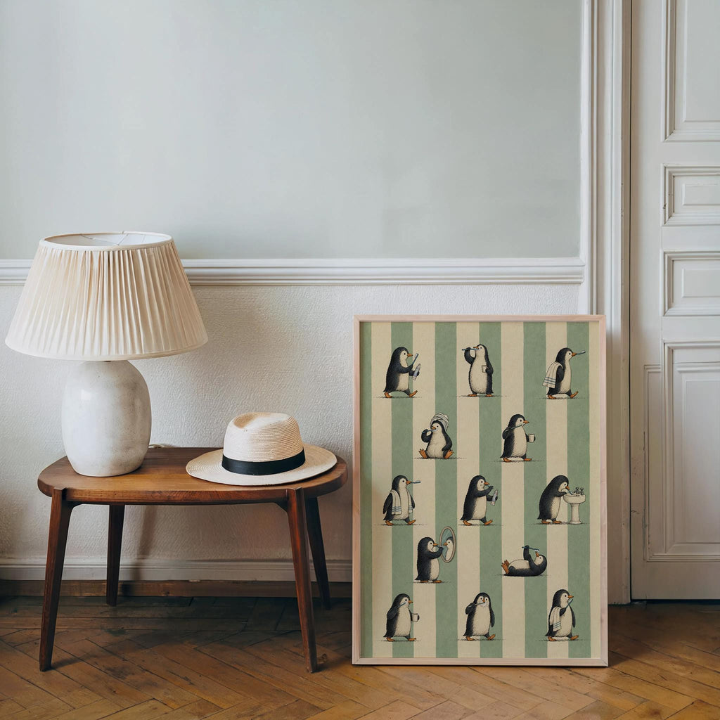Penguin lover gift display, framed whimsical animal wall art leaning by a round table with lamp and straw hat