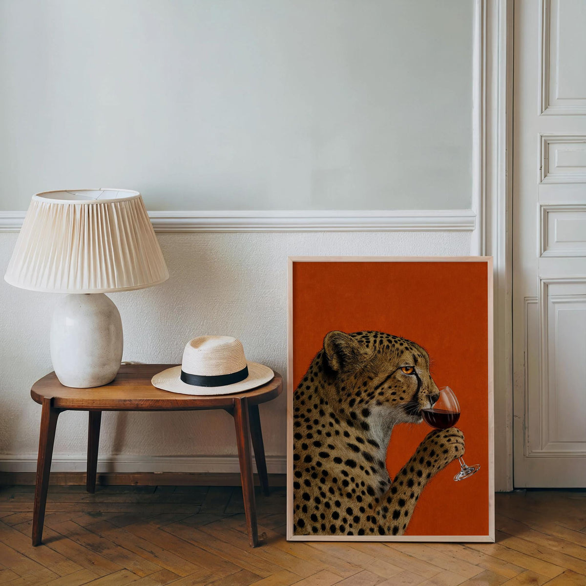 Leaning cheetah drinking wine wall art by a side table and lamp, funny cat wall art vibe, leopard wine print style