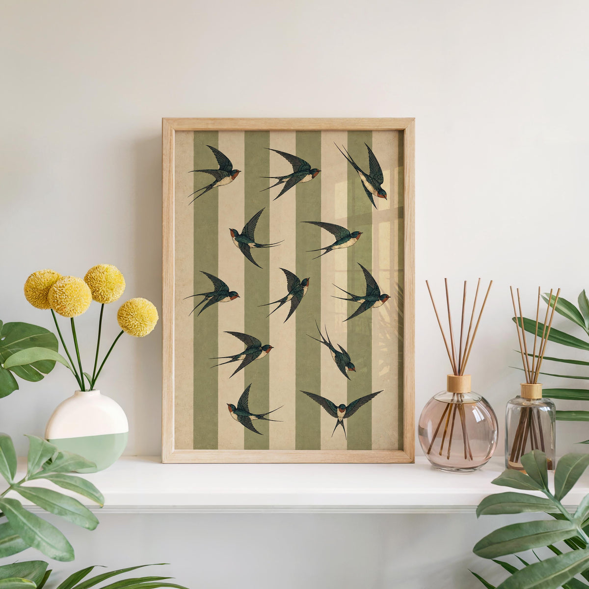 Framed green striped bird print on a mantel with vases, swallow bird wall art adding a vintage natural history feel