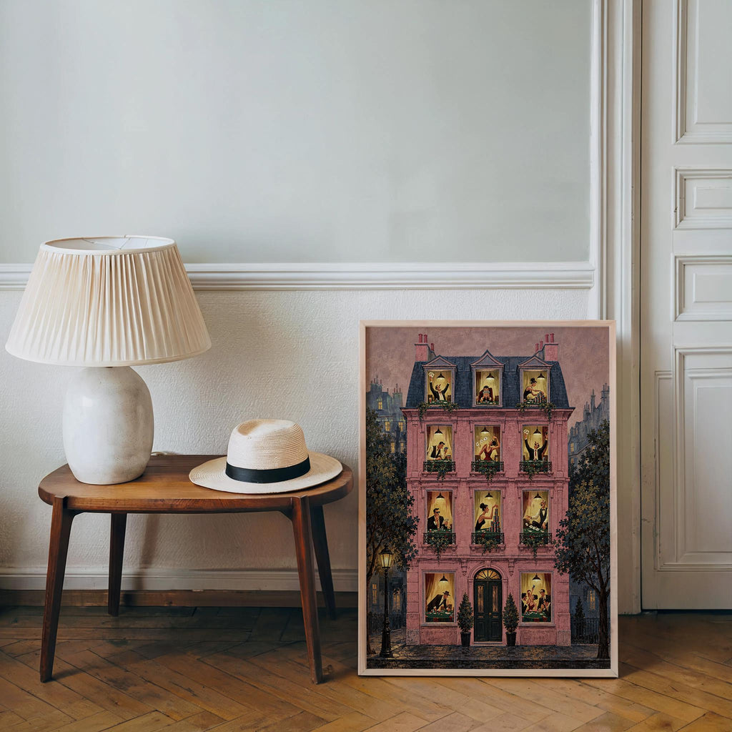 Pink Parisian building print leaning beside lamp on table, vintage poker art vibe, poker night wall art