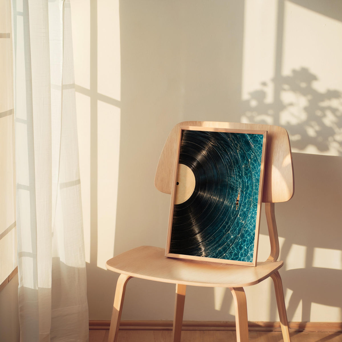 Framed vinyl record wall art perched on a chair by a sunlit window, soft shadows, poolside art print mood