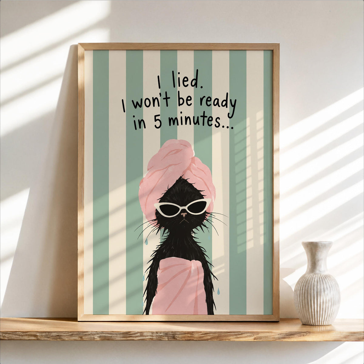 Framed funny black cat bathroom print on a wood shelf, mint stripes, pink towel, retro vibe