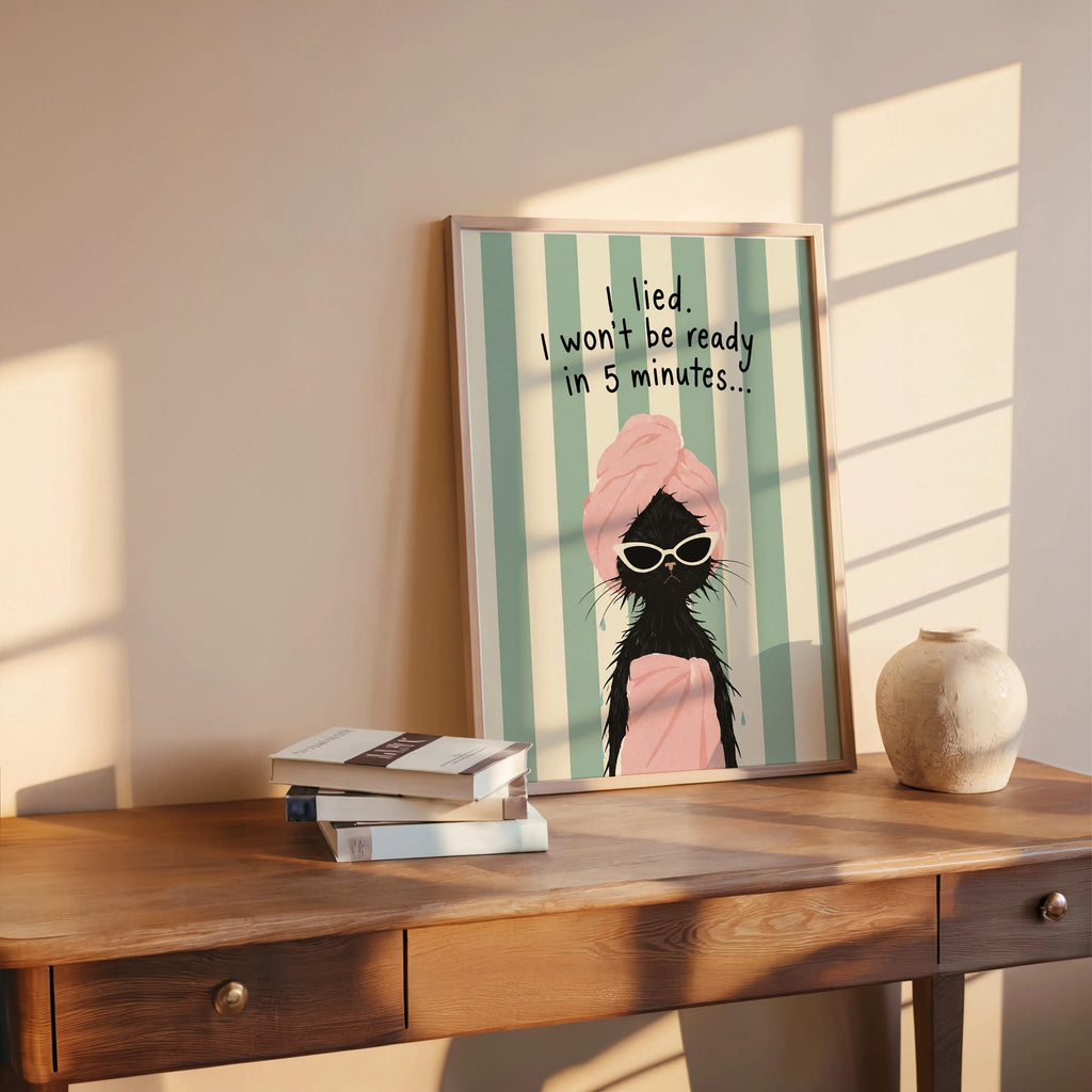 Funny cat wall art on console table, slatted sunlight, pink towel and oversized shades, vanity wall decor