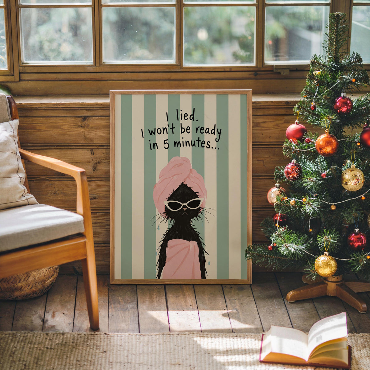 Holiday room scene, quirky bathroom poster beside decorated tree and cozy chair, mint stripes and pink towel cat