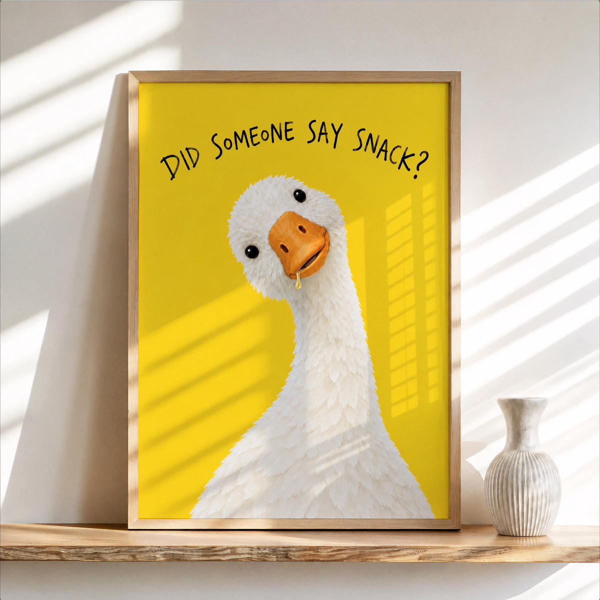 Sunlit framed yellow goose poster leaning on a wooden shelf with vase, funny goose wall art kitchen accent