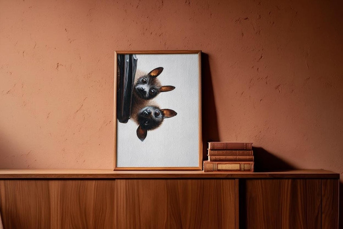 Fruit bat art print standing on wooden cabinet against terracotta wall, playful witchy wall decor feel