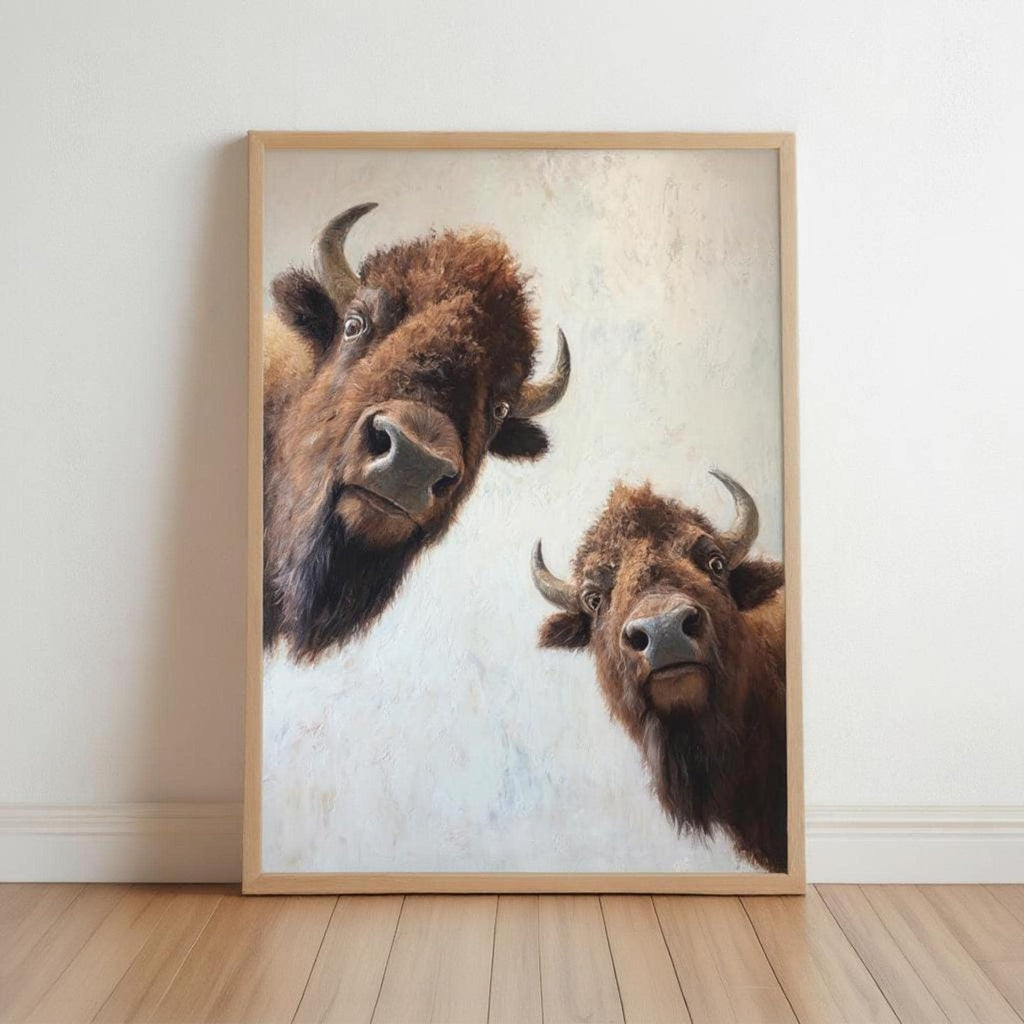 Framed bison wall art leaning on hardwood floor, two shaggy brown bison peeking, neutral palette