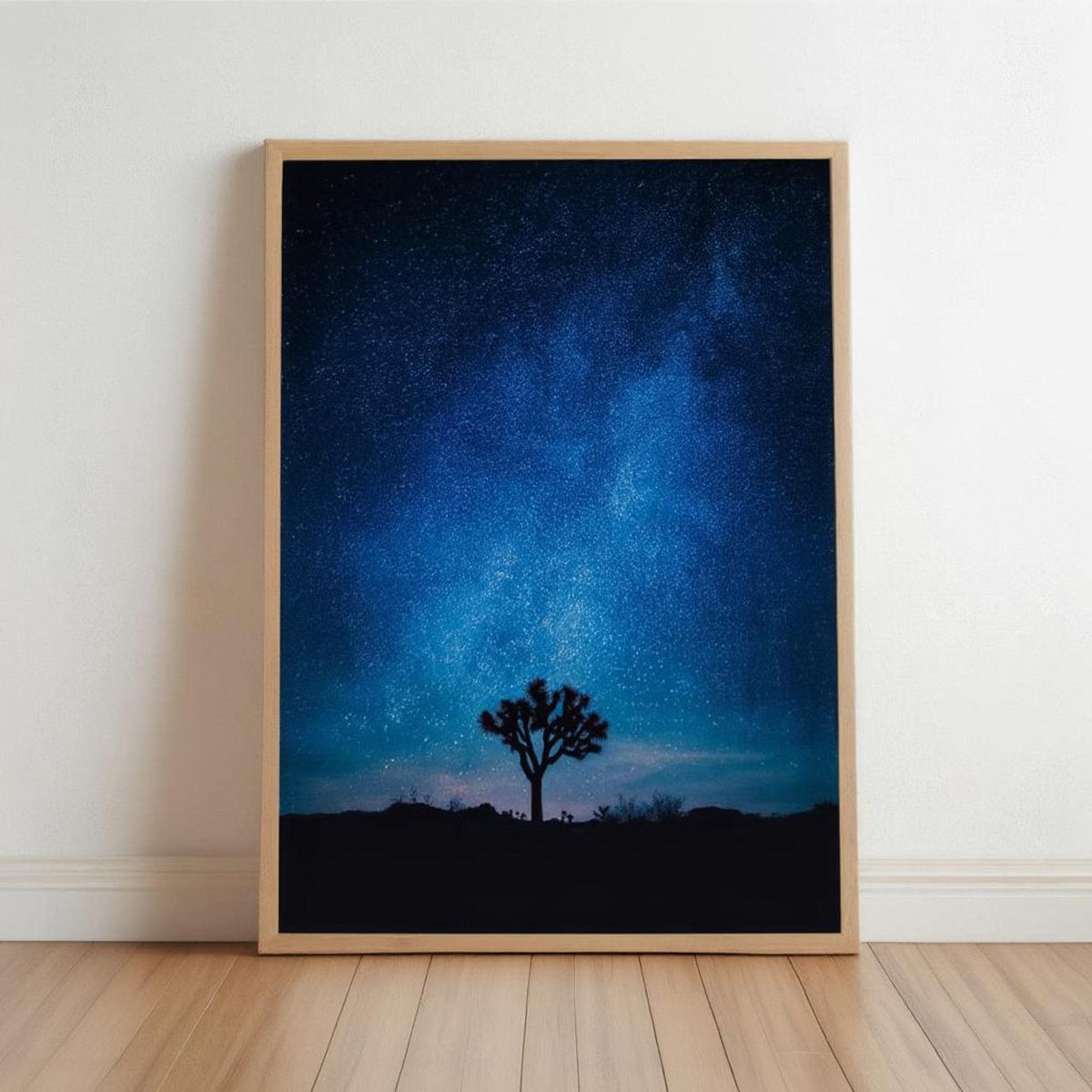 Framed vertical Joshua Tree Milky Way wall art leaning on floor, silhouetted tree against deep blue starry sky